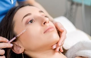 Woman Receiving a Botox Injection in the Eye Zone Lying in Bathrobe on the Medical Couch